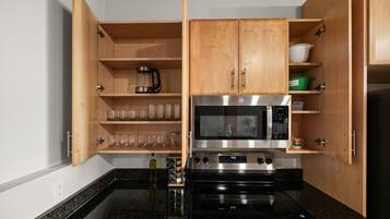 Cocina compacta con armarios de madera, microondas, horno y cafetera.