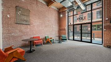 A room with brick walls, a large window with the word 'POST' on it, and several chairs and tables.