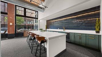 A modern kitchen with a large island, bar stools, and a view of the city through large windows.