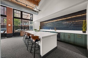 Een moderne keuken met een groot eiland, barstoelen en stadszicht door grote ramen.