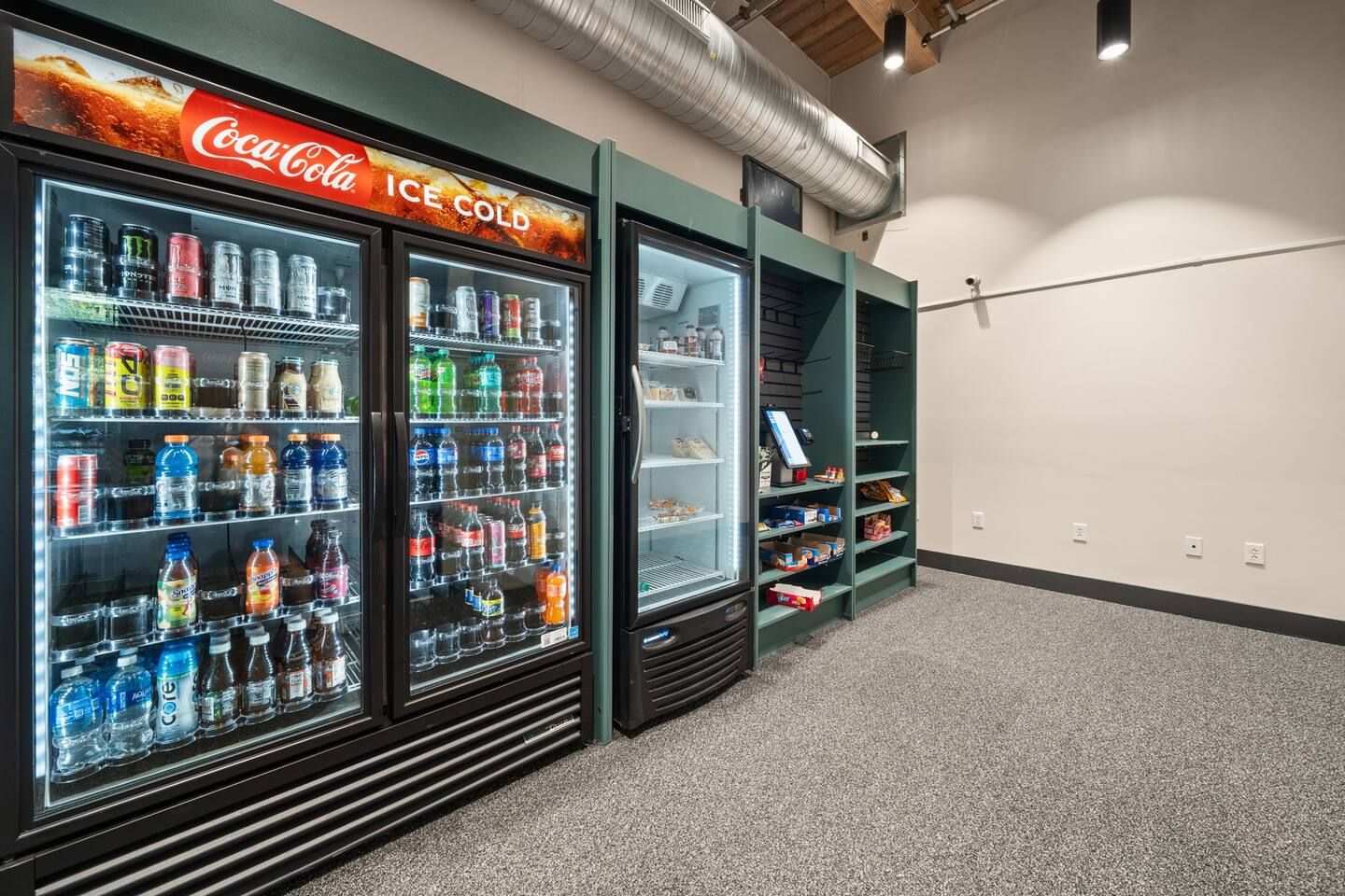 A vending machine area with Coca-Cola Ice Cold and other beverages, and a shoe display.