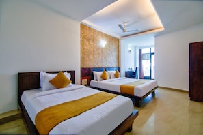 A hotel room with two beds, a ceiling fan, and a large window. - JADSTAR RESIDENCY (New Delhi)
