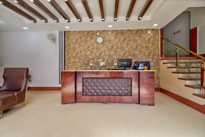 A reception desk with a clock, a computer, and a fire exit sign. - JADSTAR RESIDENCY (New Delhi)