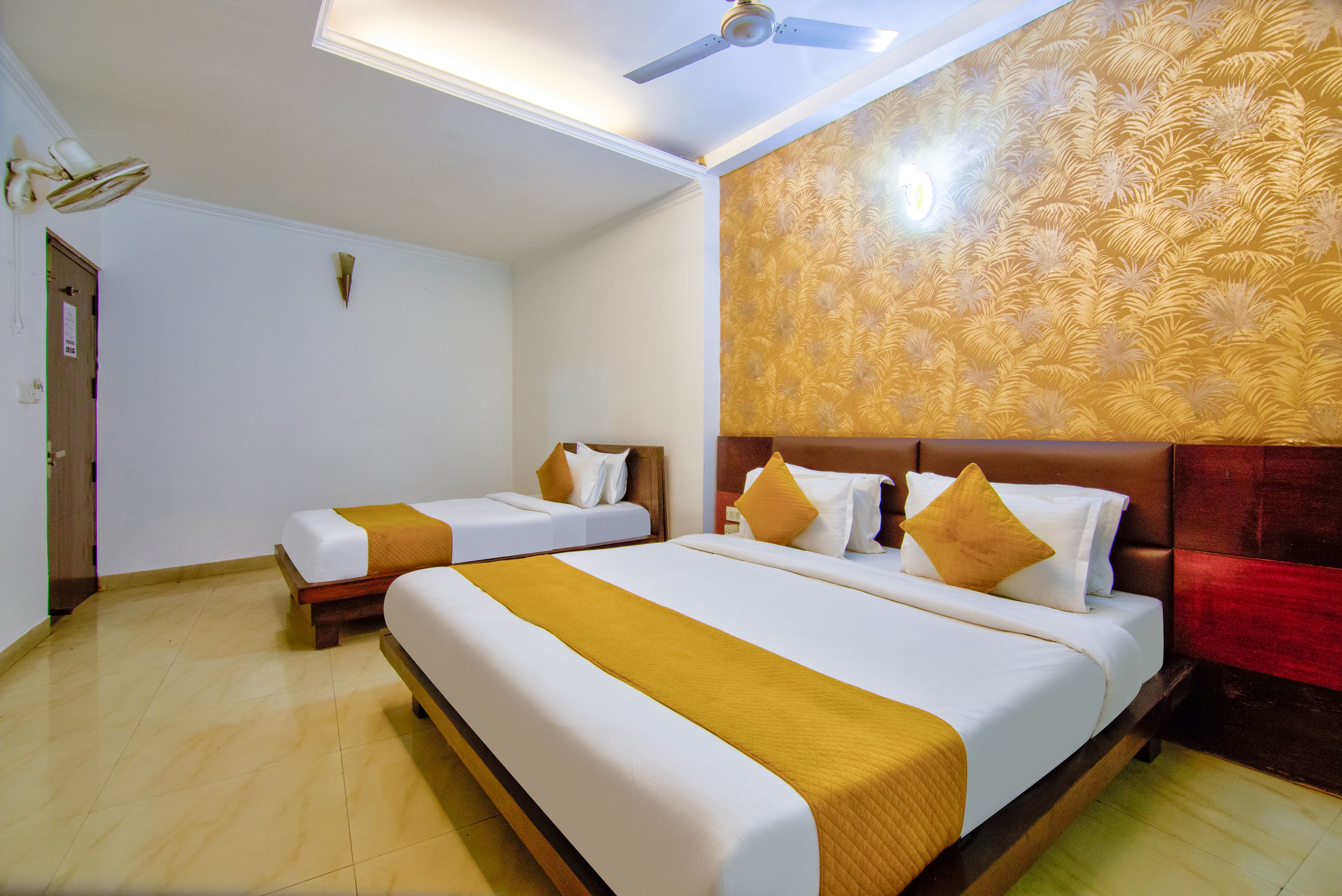 Una habitación de hotel con dos camas, un ventilador de techo y una pared con estampado.