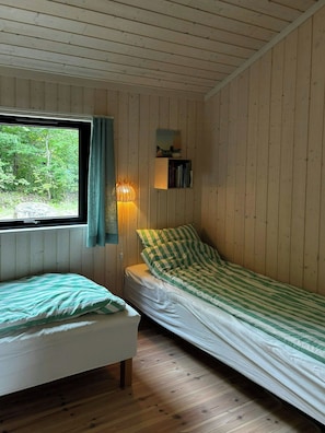 A cabin room with two beds, a window with curtains, a wall-mounted lamp, and a bookshelf. - Modern holiday home with vaulted ceiling, Tisvilde (Frederiksværk)