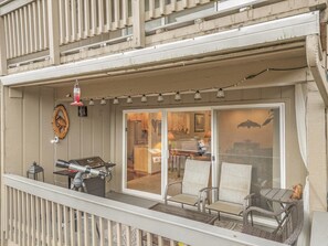 A balcony with a grill, outdoor seating, and a view into the house.