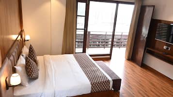Una camera d'albergo con un letto, televisione, pavimento in legno e vista sull'esterno.