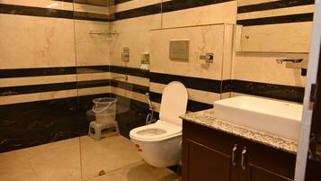A bathroom with a toilet, bidet, and a sink with a marble countertop.