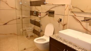 A bathroom with a toilet, shower, and sink.