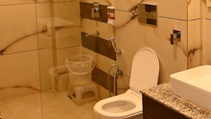 Un bagno moderno con doccia a vetro, un water e un lavabo con piano in granito.