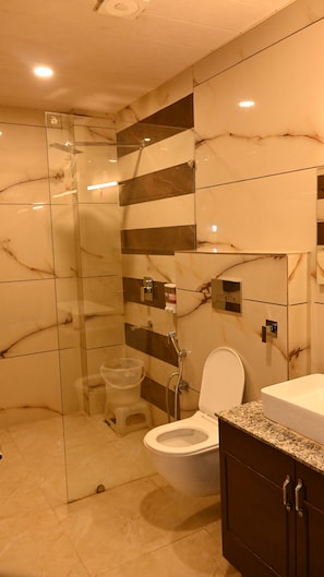 Et moderne badeværelse med en brusekabine i glas, toilet og et håndvaskarrangement med granitbordplade.
