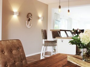 A dining area with a wooden table and chairs, a white cabinet, and wall-mounted lights. - Holiday Home in Pommerby With Swimming Pool (Pommerby)