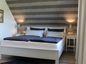 A bedroom with a bed, two bedside tables, and a wall-mounted lamp. - Holiday Home in Pommerby With Swimming Pool (Pommerby)