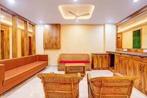 A room with a sofa, two wicker chairs, a small table, wooden cabinets, and a ceiling fan.