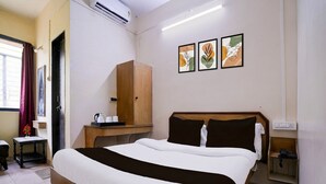 Habitación de hotel con cama, armario de madera, pequeña mesa con tetera y tazas, y aire acondicionado de pared.