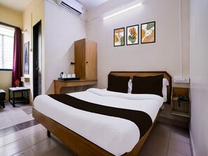 A hotel room with a bed, a wooden wardrobe, a small table with a kettle and cups, and a wall-mounted air conditioner. - Super Collection O Hubli City Center (Hubli)