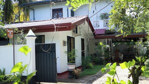 A villa with a gated entrance, a small porch, and a covered outdoor seating area. - Nature Beat Villa – Exclusive Tropical Retreat Near Mirissa (kamburugamuwa)