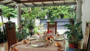 An outdoor dining area with a table set for two, surrounded by potted plants and a wooden pergola. - Nature Beat Villa – Exclusive Tropical Retreat Near Mirissa (kamburugamuwa)