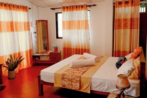 Quarto de hotel com cama, mesa de cabeceira, espelho e cortinas.