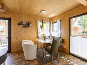 A wooden interior with a dining area, a sofa, and a window with curtains. - Cabin With 1 Bedroom (Sankt Georgen am Kreischberg)