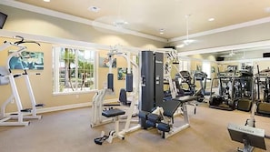 A gym with various exercise equipment, large windows, and a carpeted floor. - Bella Vida Home w Pool - Near All Parks (Kissimmee)