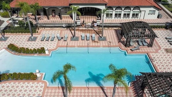 A swimming pool with lounge chairs and a covered area.