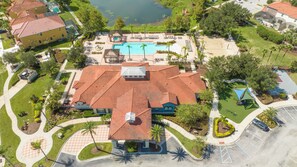 An aerial view of a residential area with a swimming pool, a covered patio, and a landscaped park. - Prime Location Near Disney at Bella Vida Resort (Kissimmee)