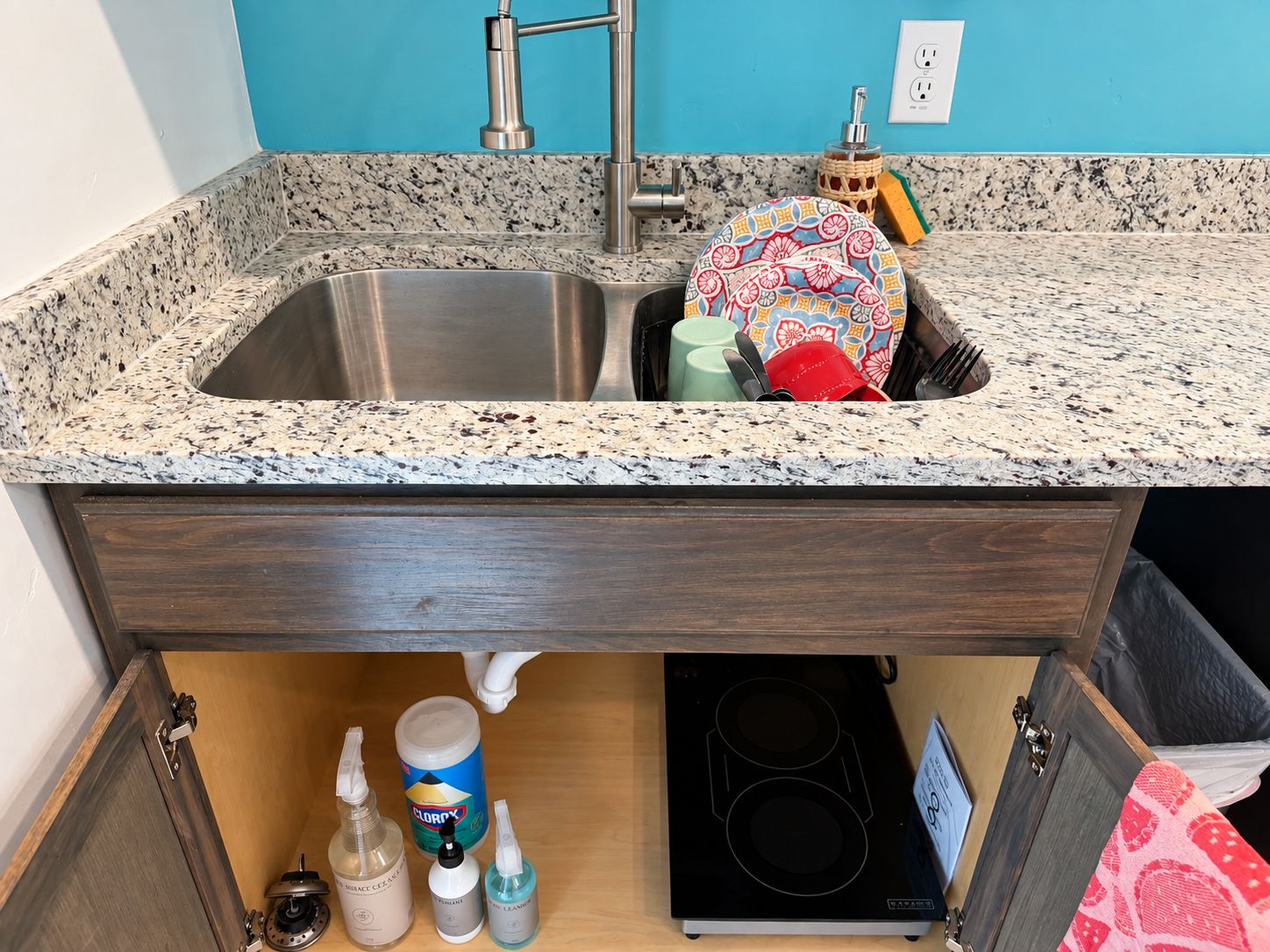 Una cocina con encimera de granito, pileta de acero inoxidable y estufa empotrada.