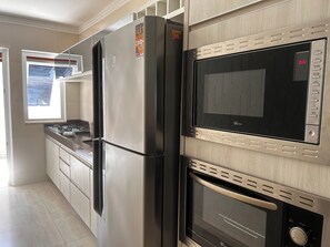 Eine Küche mit einem Edelstahl-Kühlschrank, einem Einbauofen und einer Mikrowelle.