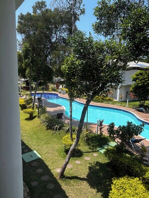 Piscina rodeada por vegetação exuberante e algumas cadeiras de descanso.