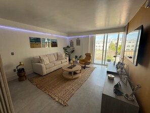 A modern living room with a sofa, coffee table, and a large window offering a city view. - Cozy 1-bedroom apartment in wonderful Miami Beach with AC (Miami Beach)