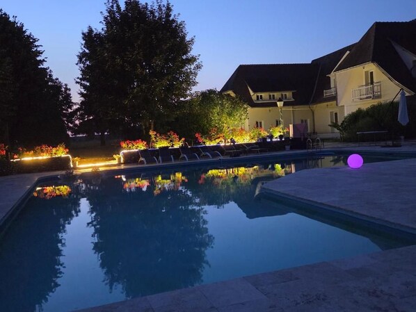 A swimming pool with a reflection of trees and a building in the background.