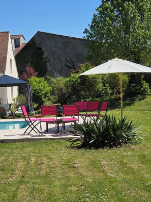 A poolside area with red chairs and a white umbrella.
