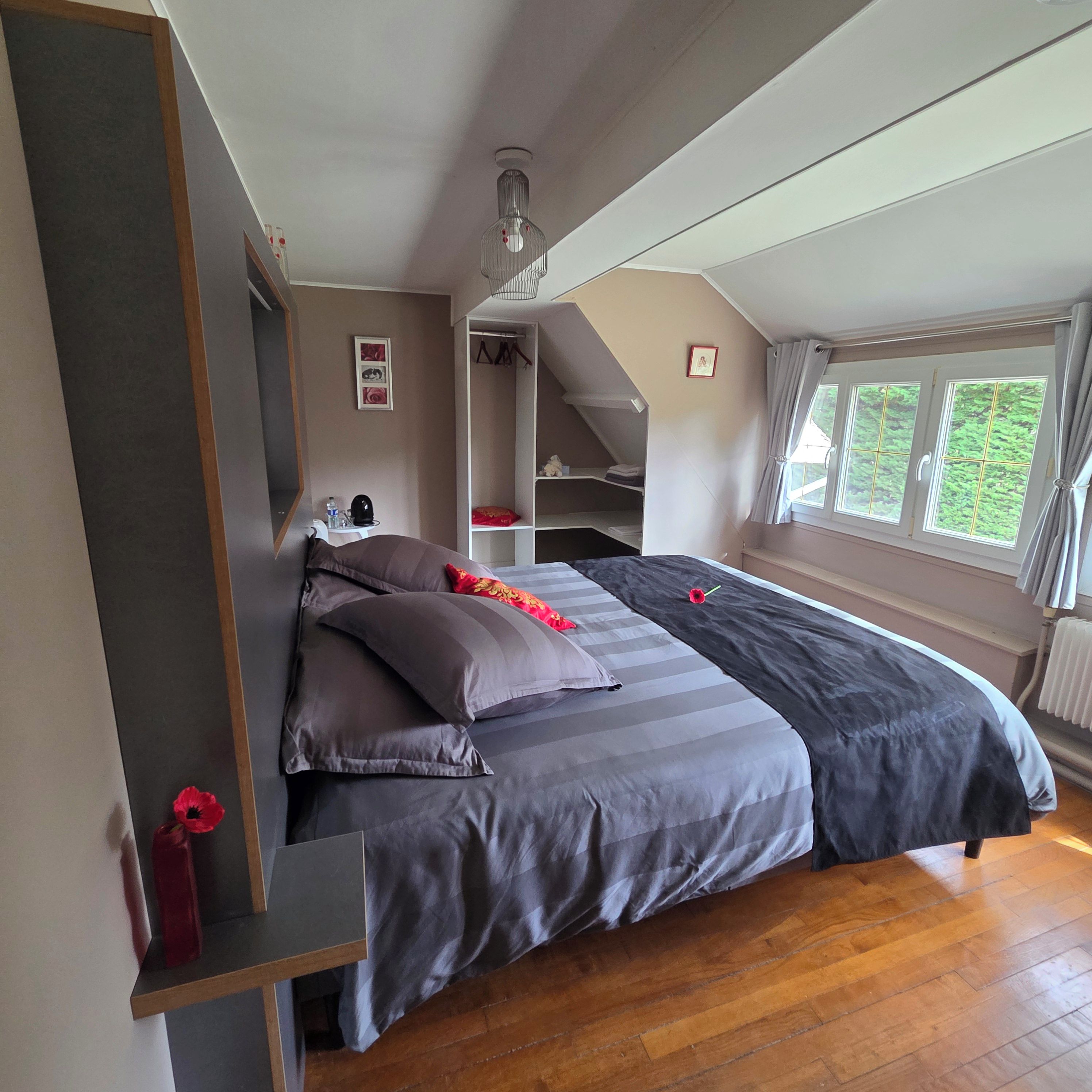 Une chambre à coucher avec un lit, une table de chevet, une armoire et une fenêtre.