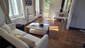 Een ruime woonkamer met een bank, salontafel en uitzicht op het groen.