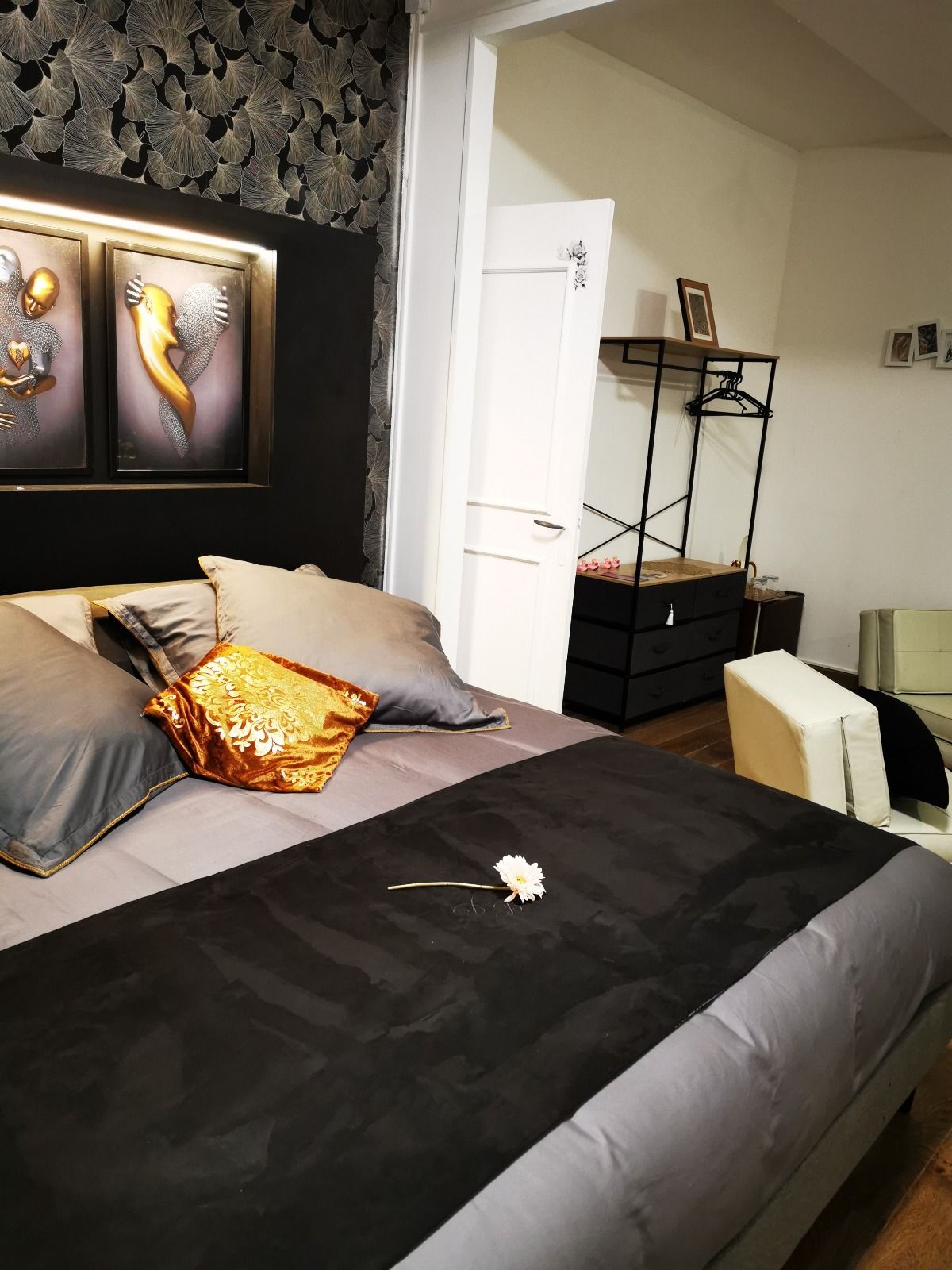 A bedroom with a bed, a dresser, a chair, and a door leading to another room.