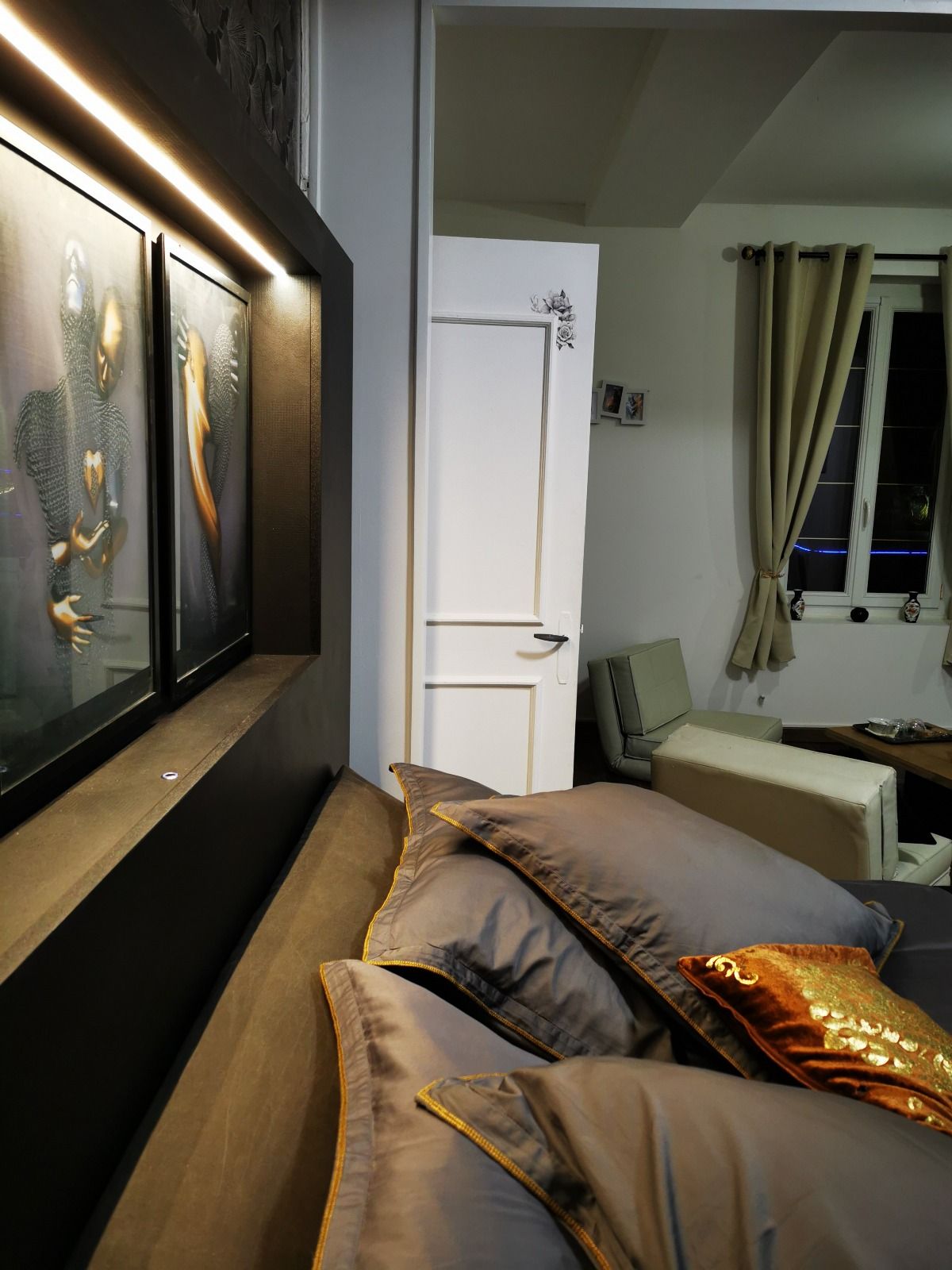 Un dormitorio con cama, mesita de noche, silla y ventana con cortinas.