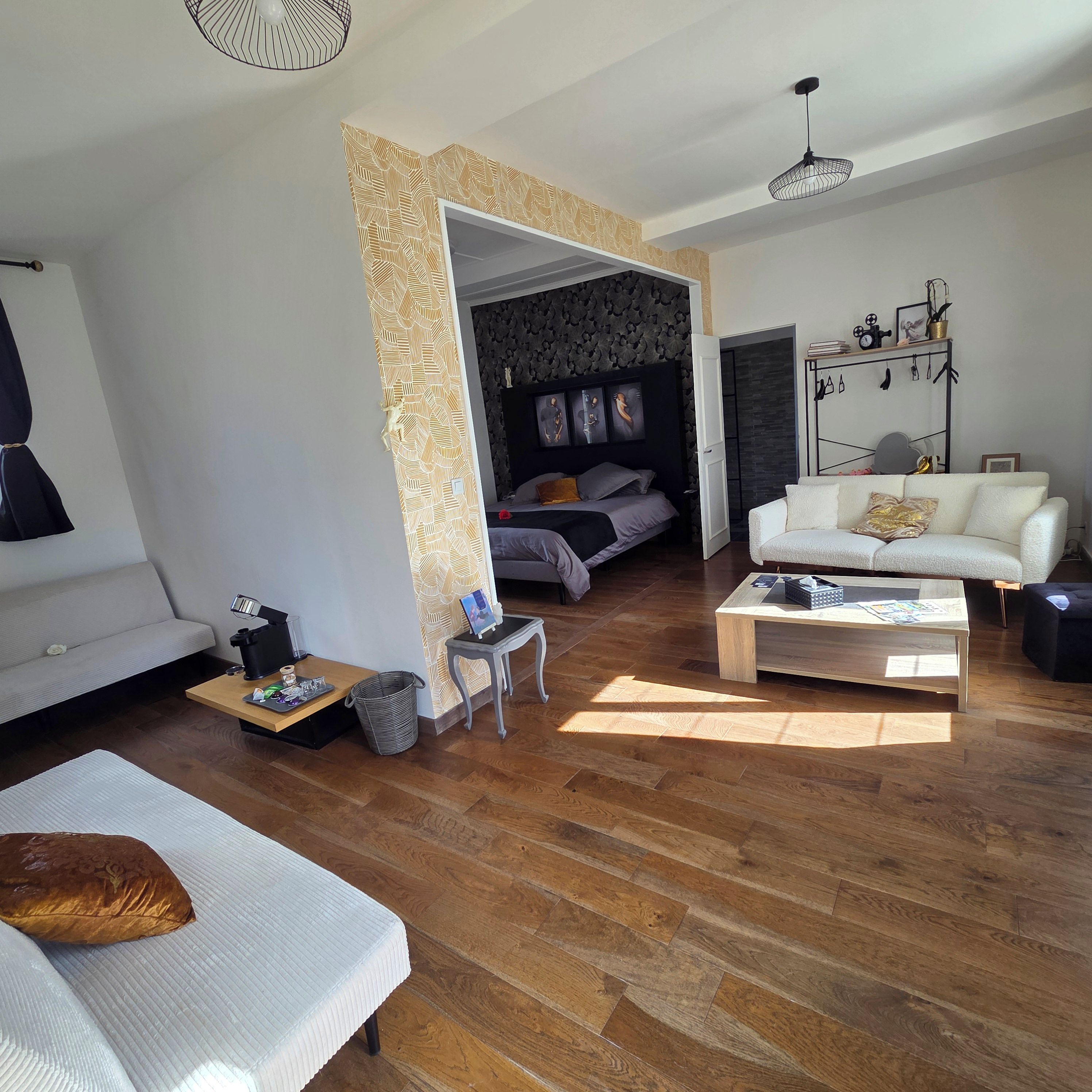 Un salon moderne avec un canapé, une table basse et un lit doté d’une tête de lit.