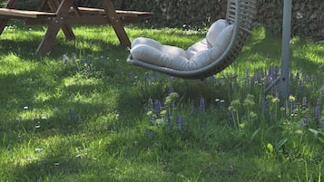 A garden with a swing chair, a picnic table, and a stone wall.