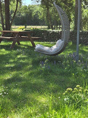 A garden with a swing chair, a picnic table, and a stone wall.