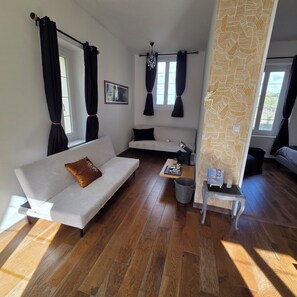 A modern living room with a sofa, a small table, a patterned wall, and a window with curtains.