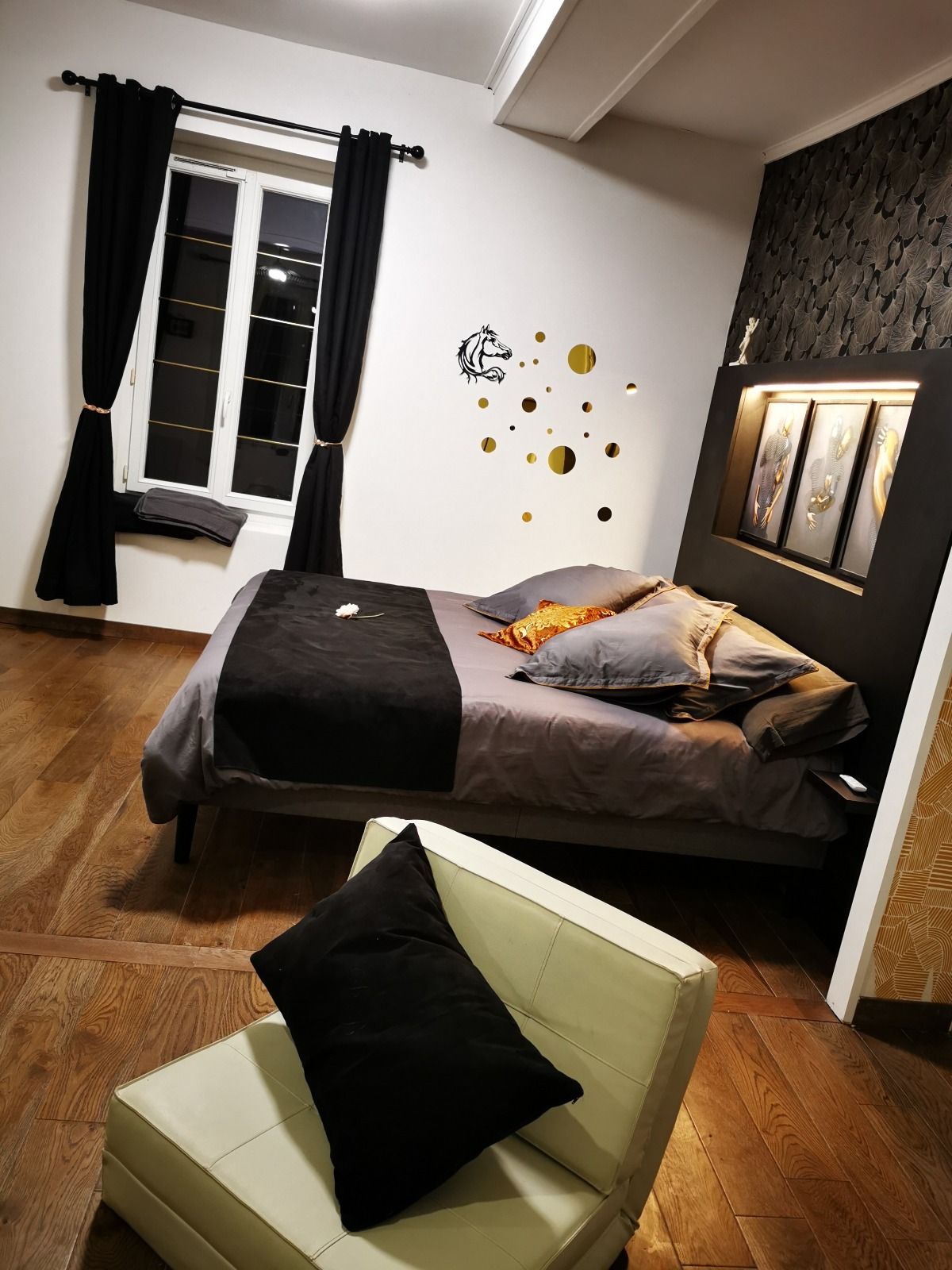 Een slaapkamer met een bed, een stoel, een raam met gordijnen en decoratie aan de muur.
