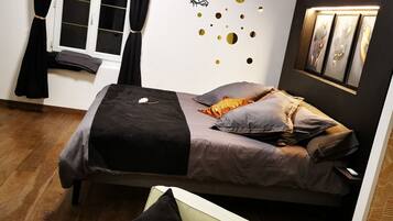Een slaapkamer met een bed, een stoel, een raam met gordijnen en decoratie aan de muur.