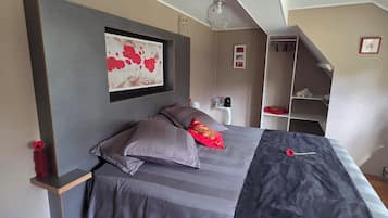 Une chambre à coucher comprenant un lit, une table de chevet, une étagère, un tableau encadré et un luminaire suspendu.
