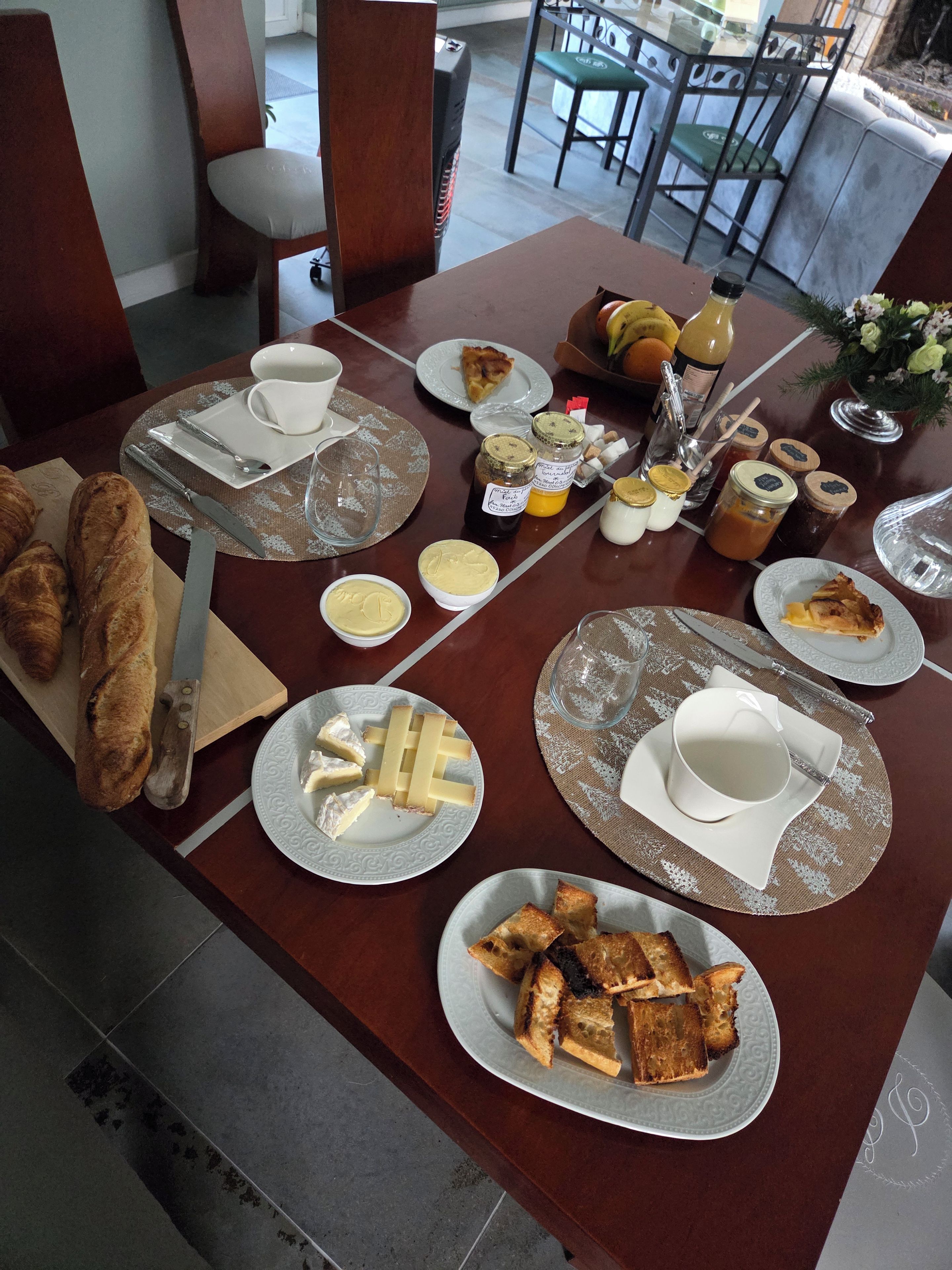 Una mesa de comedor dispuesta con diversos alimentos, incluyendo pan, queso y salsas.