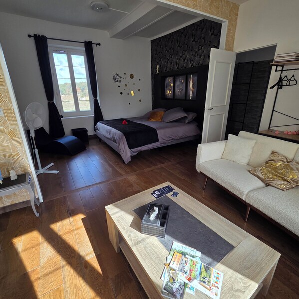 A modern living space with a bed, sofa, and a coffee table with magazines.