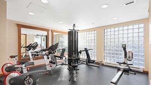 Un gimnasio con máquinas de cardio, equipo de levantamiento de pesas y amplias ventanas.