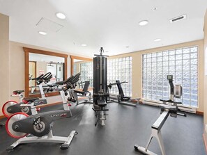 A gym with cardio machines, weightlifting equipment, and large windows. - Main Village Condo | Walk to Lifts | Free Parking (Whistler)