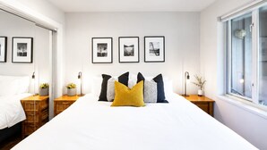 Un dormitorio con una cama grande, mesitas de noche, un armario y cuadros en la pared.