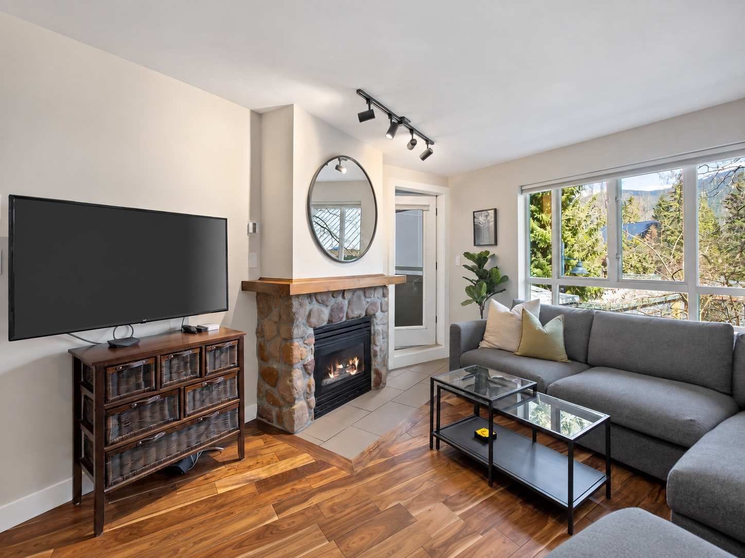A living room with a fireplace, a television, a sofa, and a large window.